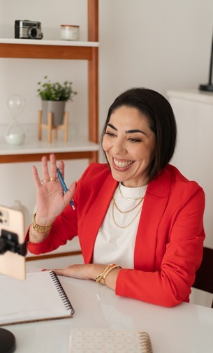 Larissa Bez em atendimento online, acenando durante uma videochamada