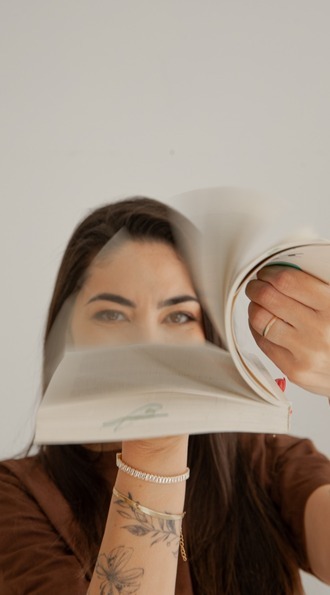 Larissa Bez folheando um livro diante do rosto